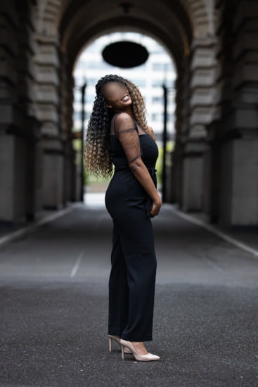 Elegant black woman in a long black dress standing in a London street