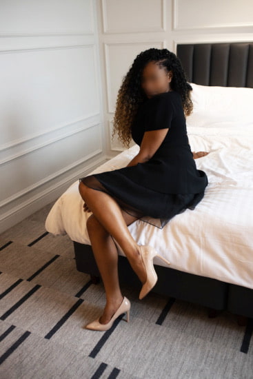 Beautiful black woman sitting on a hotel room bed