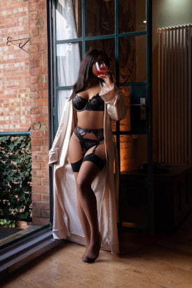 Tall ebony girl in sexy lingerie sipping a glass of wine by an open French door